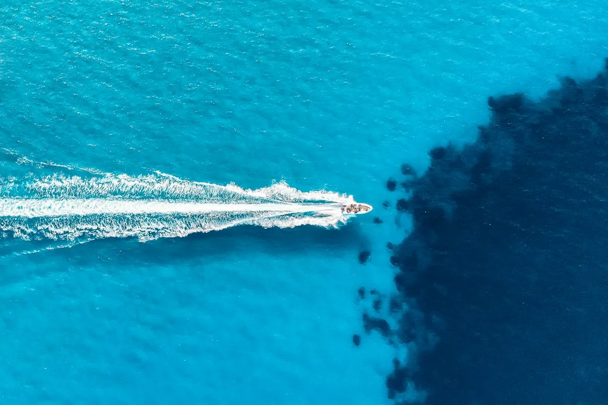 Vue aérienne d'un bateau à moteur blanc filant sur une eau turquoise