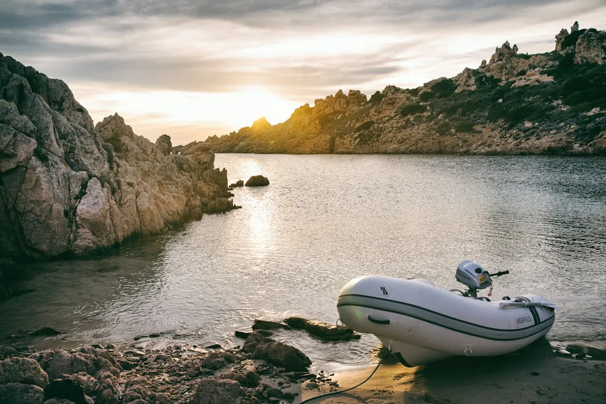 Annexe gonflable échouée sur une plage rocheuse au coucher du soleil