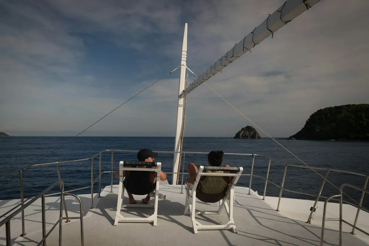 Deux personnes détendues à l'avant d'un catamaran face à l'océan