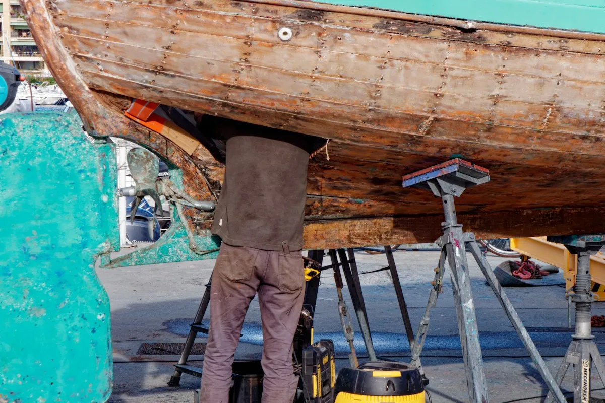 Personne travaillant sous la coque d'un bateau en cale sèche