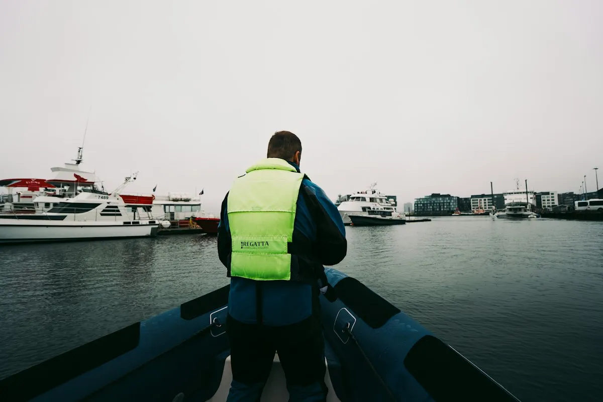 Personne portant un gilet de sécurité jaune à l'avant d'un bateau dans un port