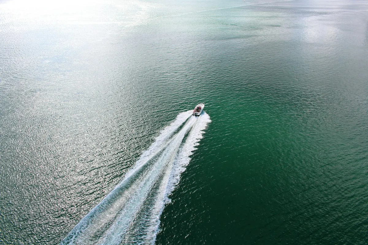 Vue aérienne d'un bateau à moteur isolé filant sur une mer turquoise