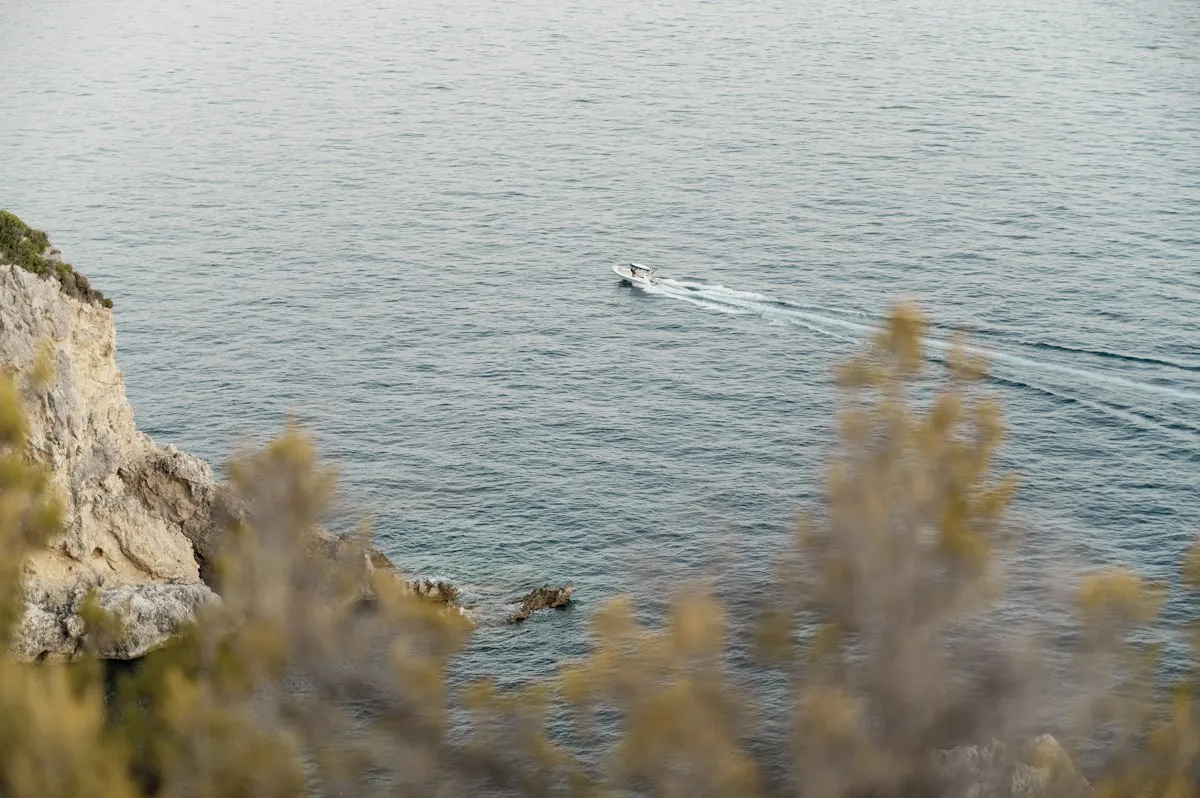 Bateau longeant une côte rocheuse méditerranéenne