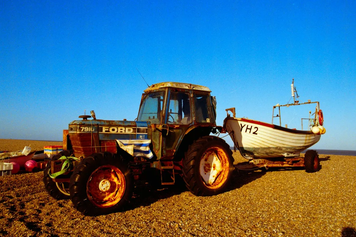 Tracteur tirant un bateau sur remorque le long d'une plage de galets