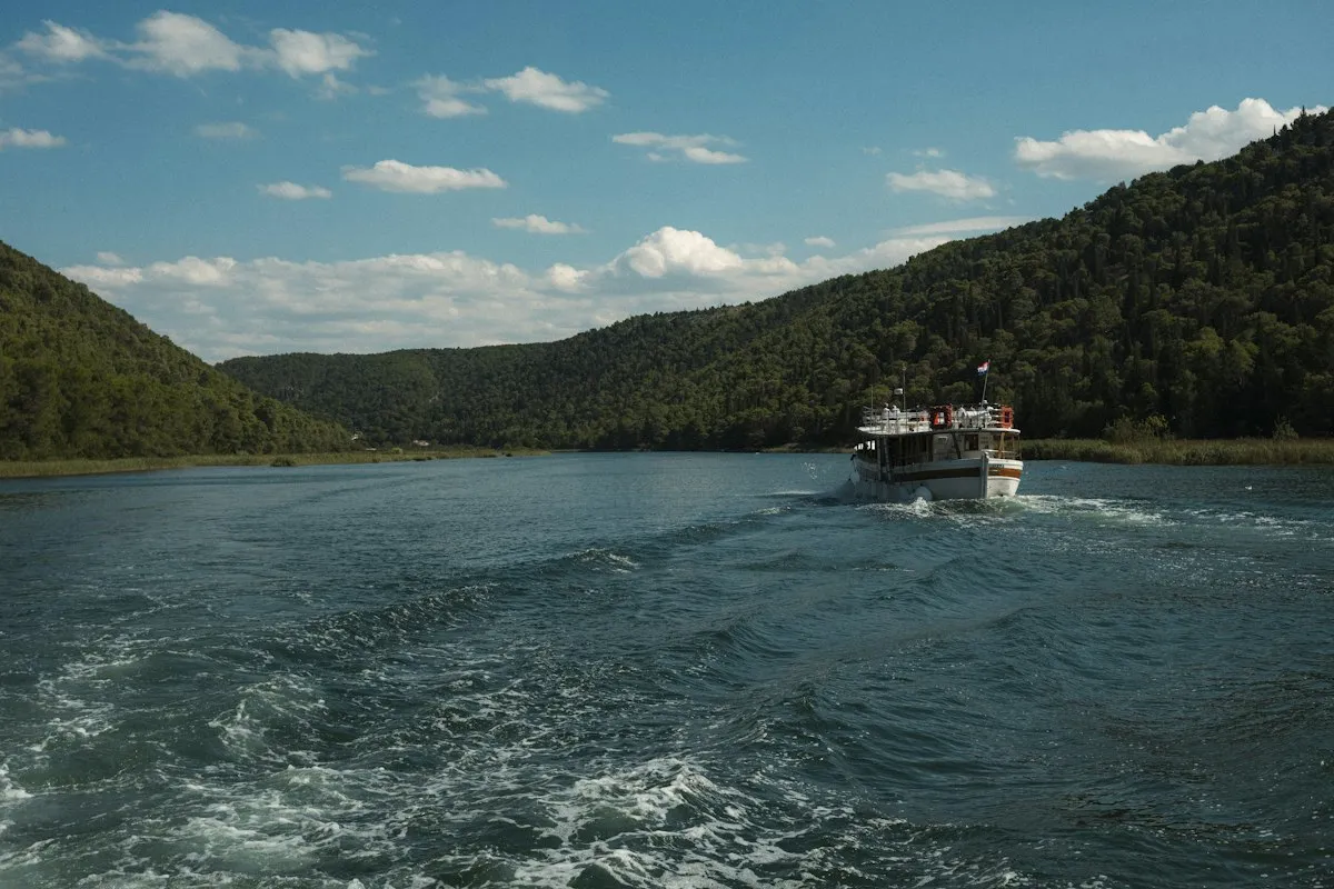 Bateau de croisière fluviale naviguant entre des collines boisées