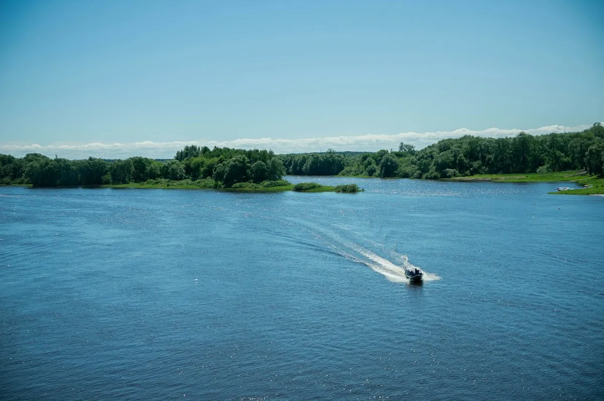 Bateau à moteur sur une large rivière aux berges vertes