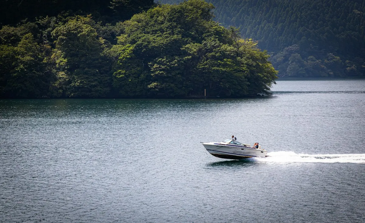 Petit bateau à moteur laissant un sillage blanc sur un lac de montagne