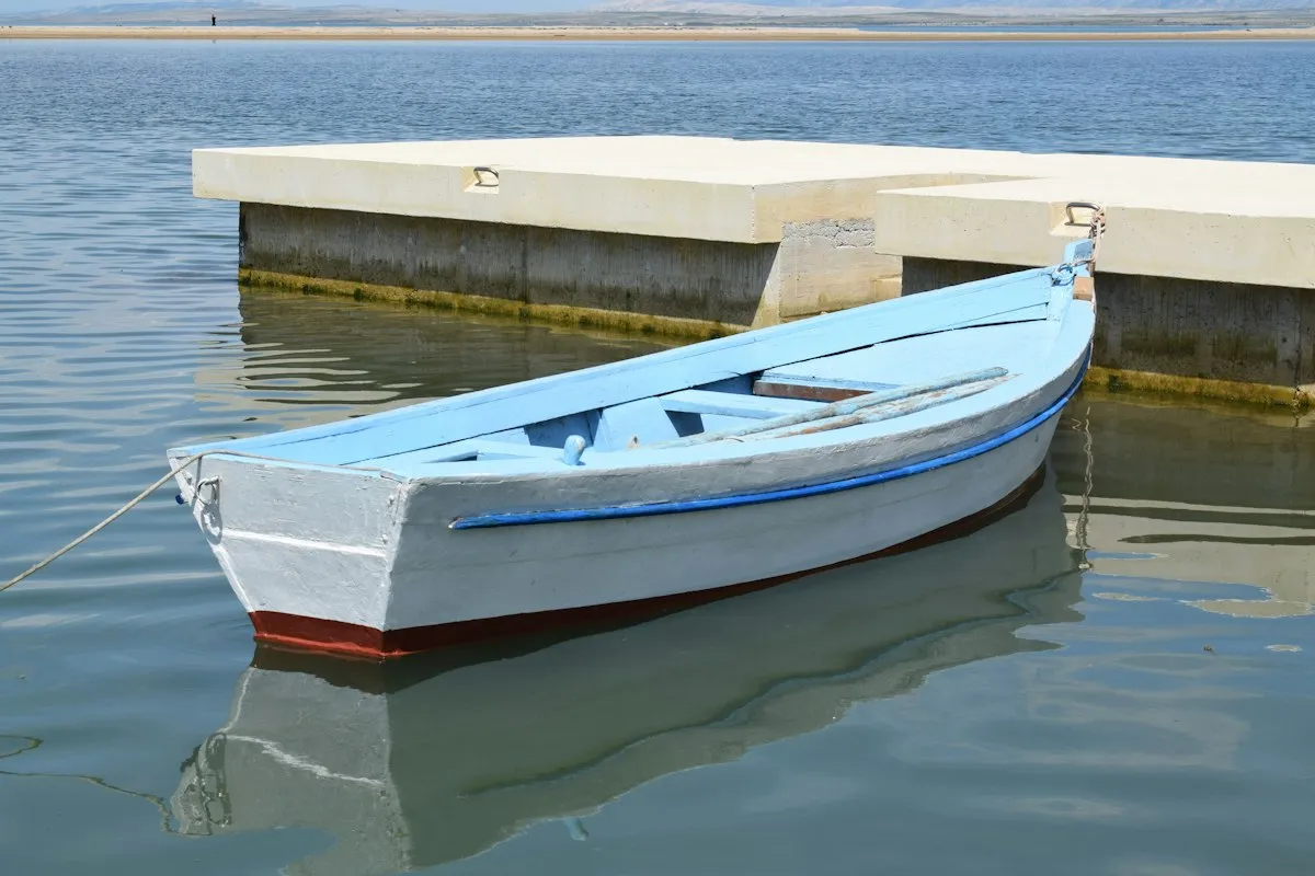 Petite barque bleue amarrée le long d'un quai en béton