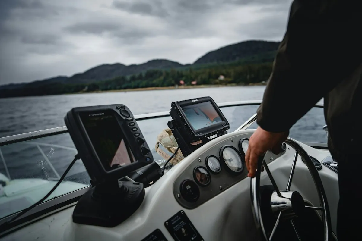 Main sur la barre d'un bateau équipé de deux traceurs GPS