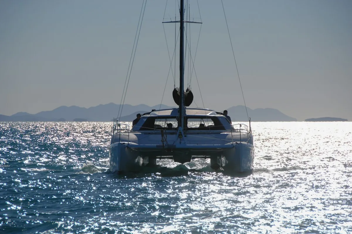 Catamaran de croisière naviguant en silhouette au coucher du soleil